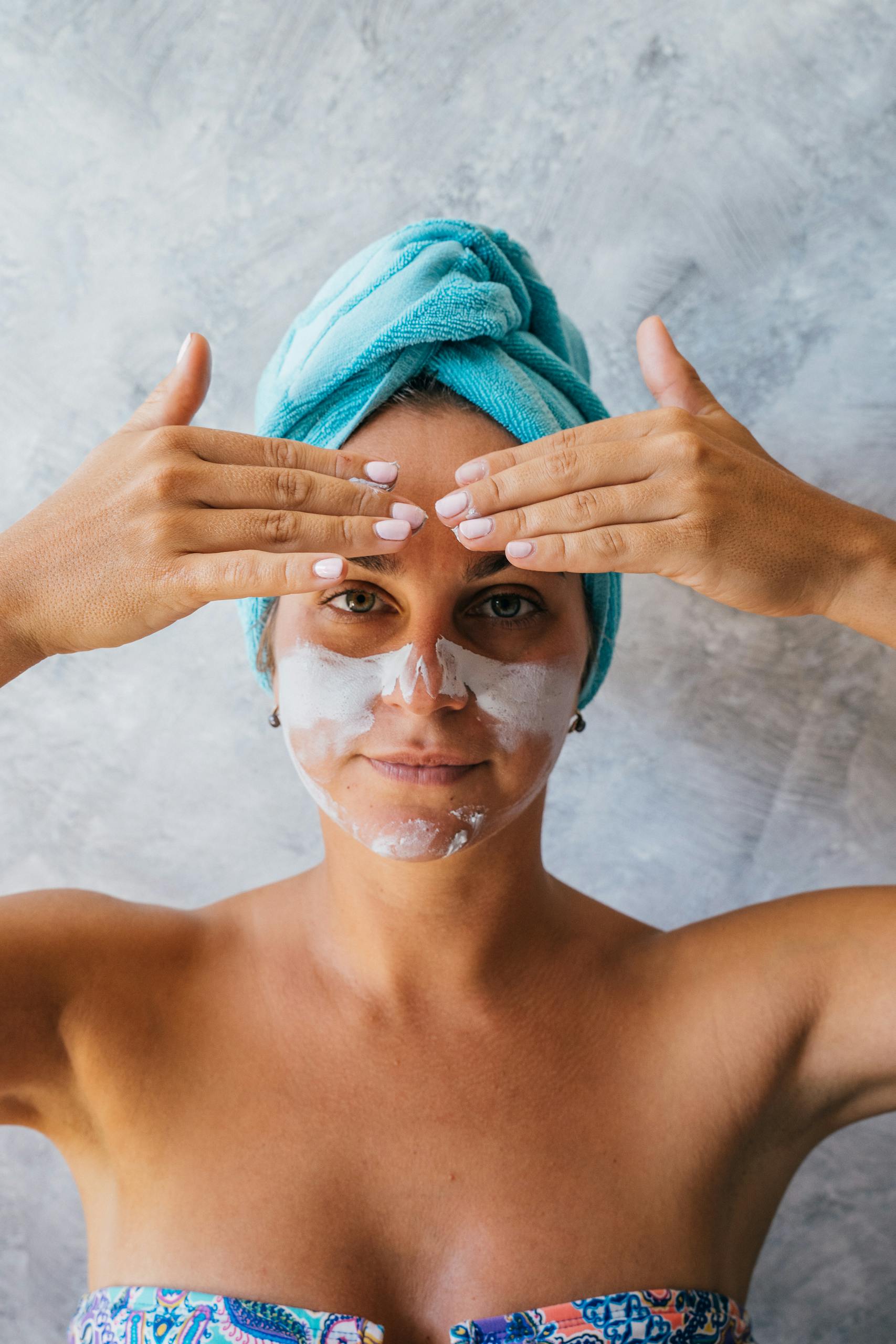 A woman applies facial cream for a moisturizing skincare routine, featuring a focus on beauty and self-care.