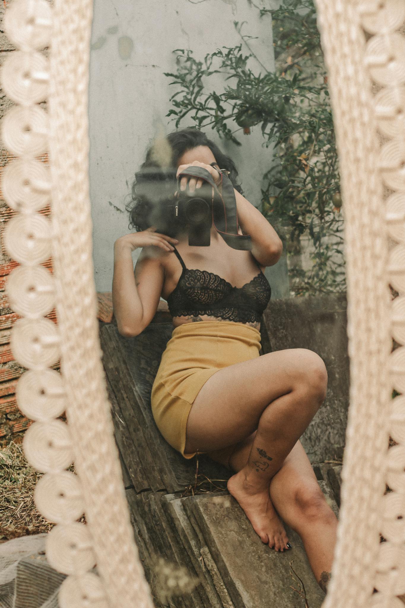 Our Mission 3 A woman captures a creative mirror selfie while posing outdoors.